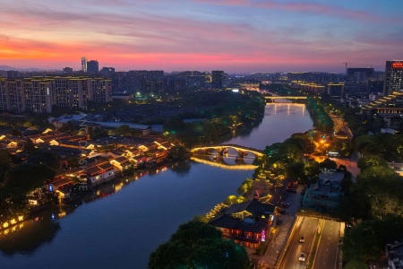 View of Hangzhou Grand Canal Sunset view of Hangzhou Grand Canal, illuminated ancient stone arch bridge and lit waterfront old town buildings