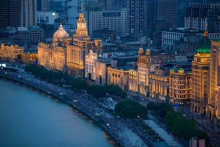 Aerial dusk view of Shanghai Bund grand historic riverside buildings and crowded waterfront promenade