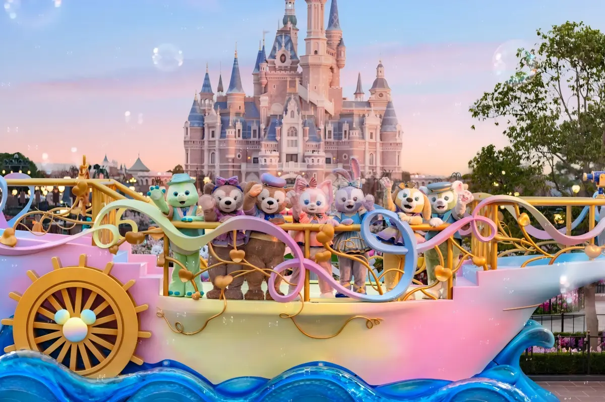 Duffy and friends on a colorful boat?shaped parade float with Enchanted Storybook Castle backdrop at sunset