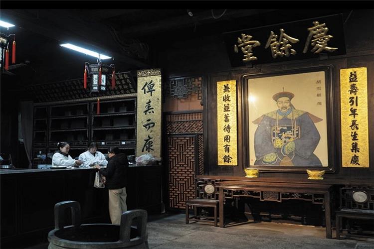 Antique interior of Hu Qing Yu Tang featuring the portrait of founder Hu Xueyan, golden calligraphy couplets and service counter for herbal medicine consultation