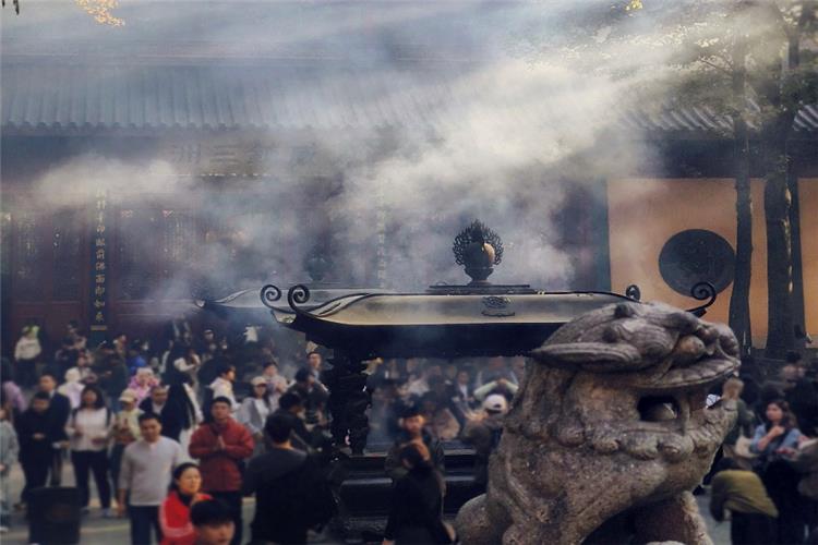 Incense Smoke at Lingyin Temple Thick curling incense smoke rising from bronze censer, visitors praying behind stone lion sculpture inside Lingyin Temple, Hangzhou