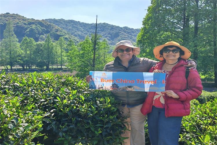 Our lovely foreign guests holding our banner and taking memorable photos among vibrant green Longjing tea terraces in Hangzhou Meijiawu Village