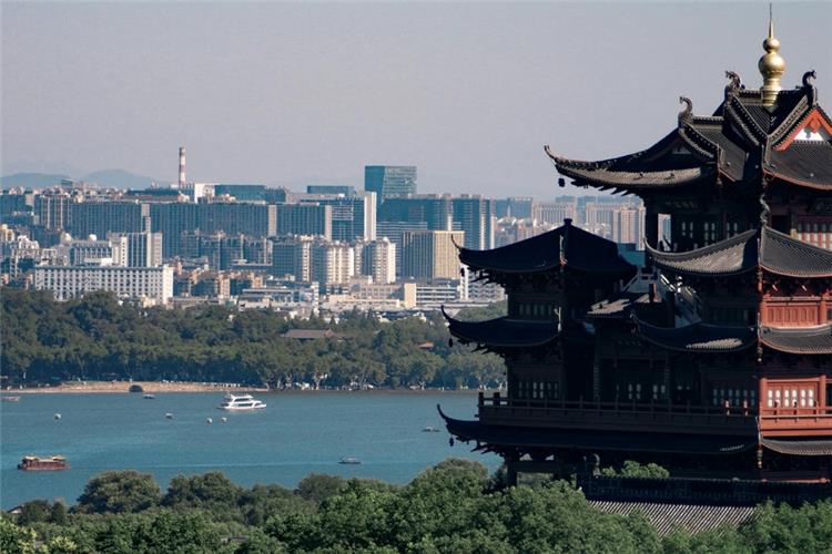 Ancient Chenghuang Pavilion overlooking West Lake, cruise boats and Hangzhou city skyline