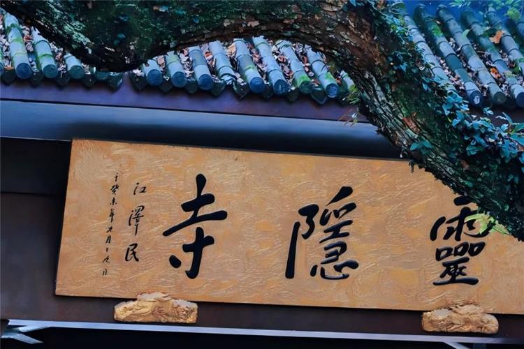 Lingyin Temple in Hangzhou showing ancient Buddhist temple with upturned eaves, incense burners, green mountain forests and Feilai Peak stone Buddha carvings