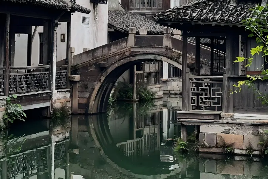 Wuzhen Water Town in Jiaxing showing well-preserved classic Jiangnan canal town with black-tiled waterside houses, stone arch bridges, black-awning rowing boats and lantern-lit ancient alley scenery