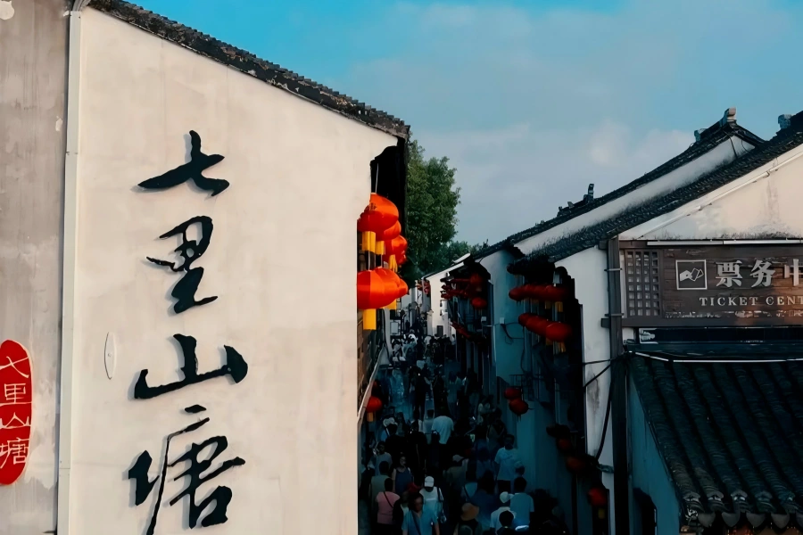Shantang Street in Suzhou featuring white-wall black-tile waterside dwellings, stone arch bridges and wooden rowboats drifting along ancient canal