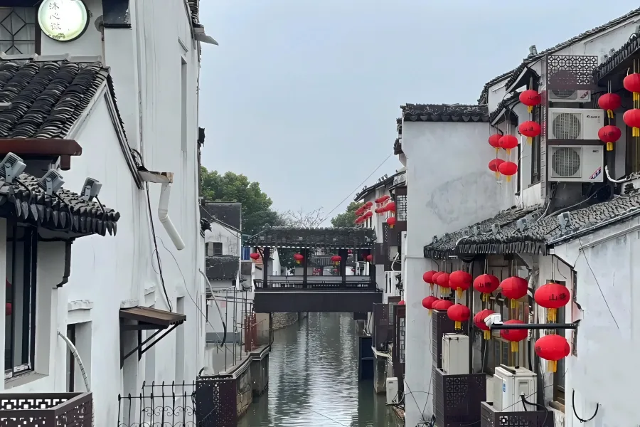 Qili Shantang Canal in Suzhou, featuring Ming and Qing waterside dwellings, stone arch bridges and wooden tourist boats floating on tranquil canal waters