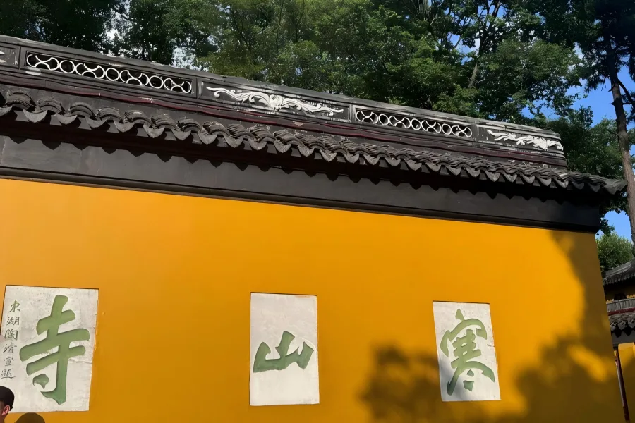 Historic Hanshan Temple in Suzhou, classic Tang-dynasty Buddhist complex with pagodas, yellow temple walls and lush surrounding greenery