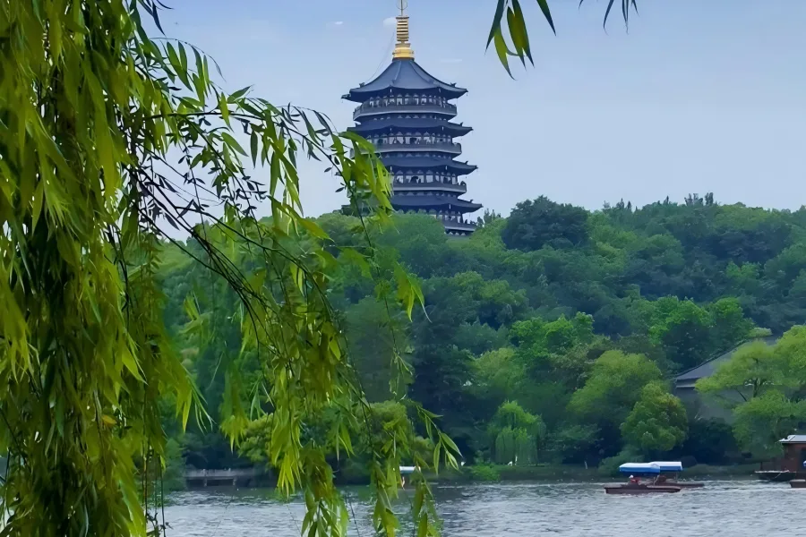 West Lake in Hangzhou showcasing mist-shrouded rolling hills, willow-lined ancient causeways, pagodas and paddle boats forming a classic UNESCO Jiangnan ink-wash landscape