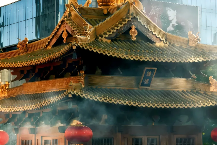Golden-roofed ancient Jing'an Temple nestled among modern skyscrapers in downtown Shanghai, with curling incense and solemn Buddhist architecture