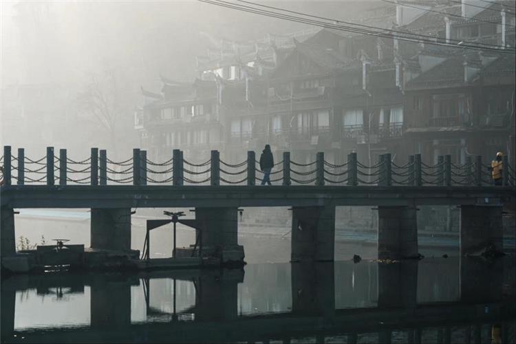 Foggy morning scene with pedestrian bridge at Fenghuang Ancient Town, Hunan