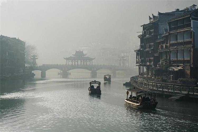 Wooden tourist boats on misty Tuojiang River at dawn, Fenghuang water town