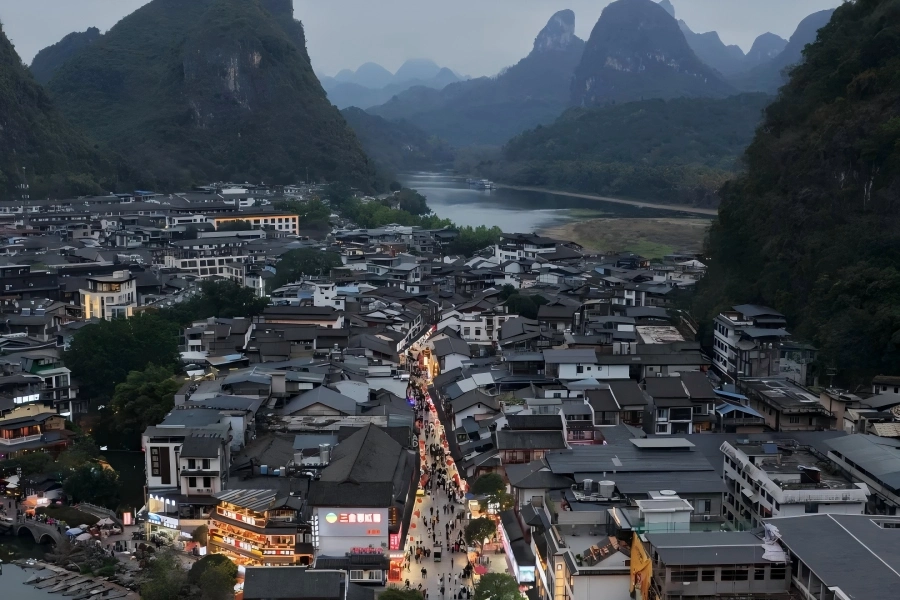 Yangshuo West Street Yangshuo West Street in Guilin showing bustling pedestrian scene along grey?brick old street, framed by distant Guilin karst hill peaks
