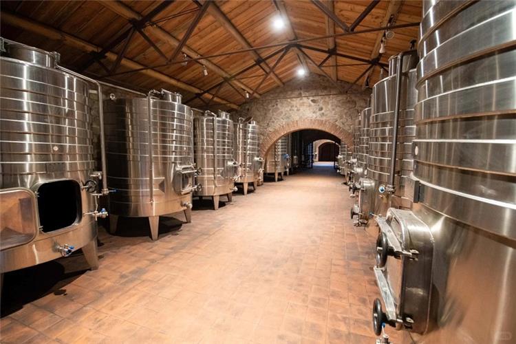 Stainless Steel Fermentation Tanks in Winery Production Hall Rows of large stainless steel wine fermentation tanks inside stone?wall winery production facility