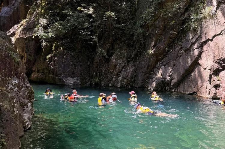 Canyoning Activity in Heilongtan Mountain Gorge Group of tourists with life vests swimming and canyoning in emerald?green canyon water at Beijing Heilongtan