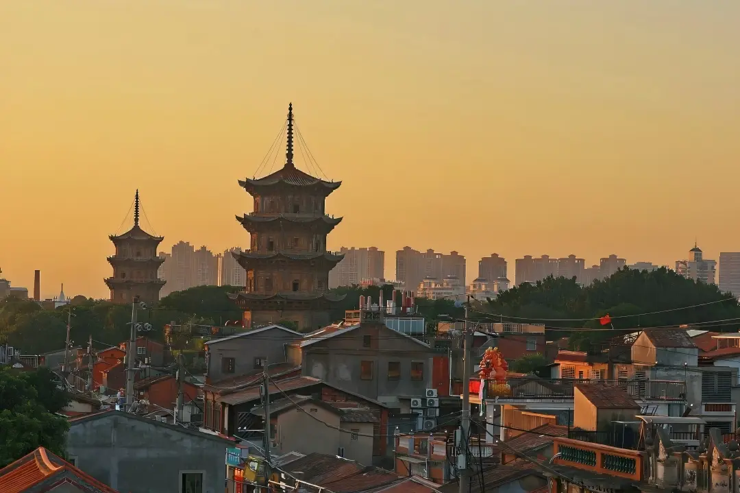Ancient stone pagodas amid old buildings in Quanzhou at golden hour