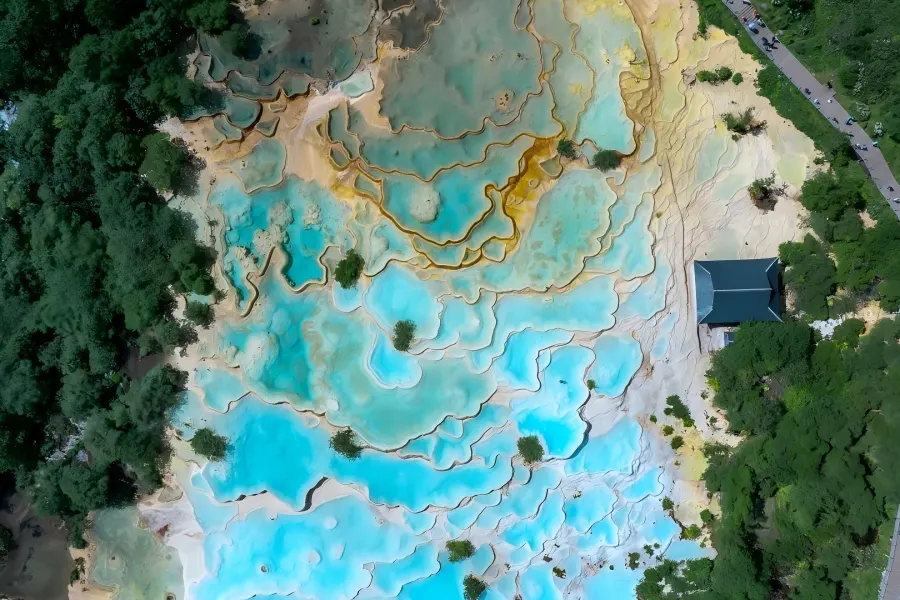 Huanglong Scenic Area，terraced travertine color?ponds, golden calcite terraces winding through high?altitude mountain valley, Sichuan world natural heritage site