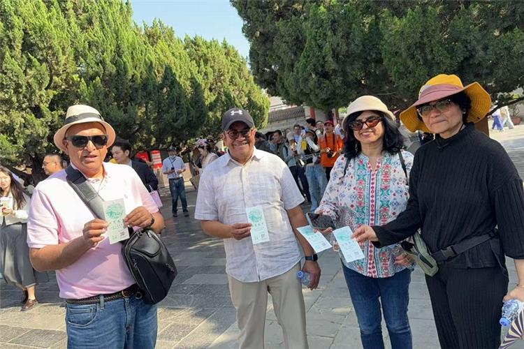 Tourists Displaying Entry Tickets Four international visitors holding up entrance tickets for sightseeing tour, trees and crowd in background