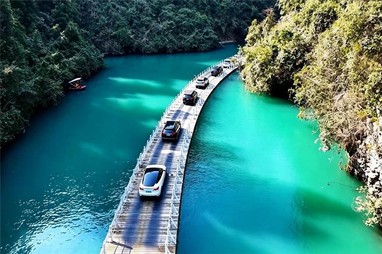 Cars on floating bridge over emerald river in Enshi