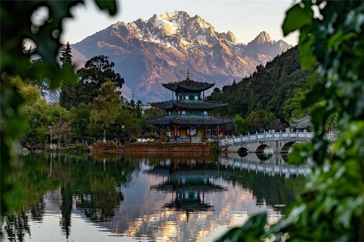 Black Dragon Pool, Lijiang with Jade Dragon Snow Mountain View Traditional Chinese pavilion reflected on lake, framed foliage, Jade Dragon Snow Mountain sunrise