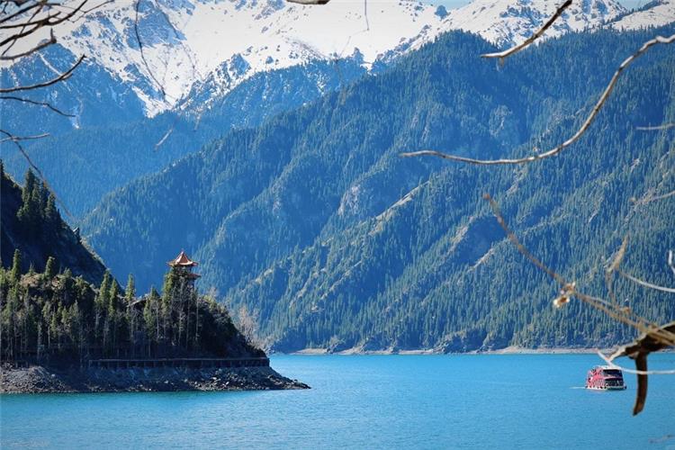 Blue alpine lake, snow?capped Tianshan mountains, traditional Chinese pavilion and sightseeing boat at Tianchi Lake Xinjiang