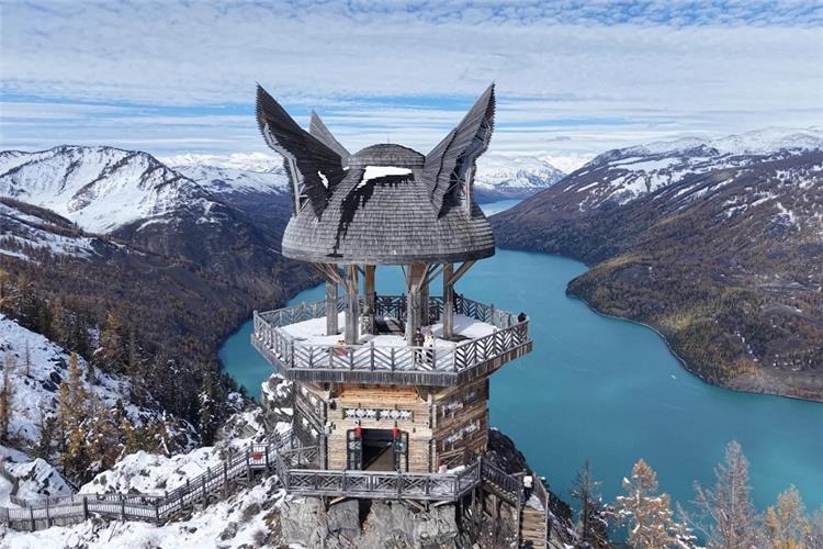 Kanas Guanyu Tai Observation Deck overlooking Kanas Lake, Altay Xinjiang Iconic wooden Guanyu Tai viewing tower on mountain top overlooking turquoise Kanas Lake, snow?capped Altai mountains background