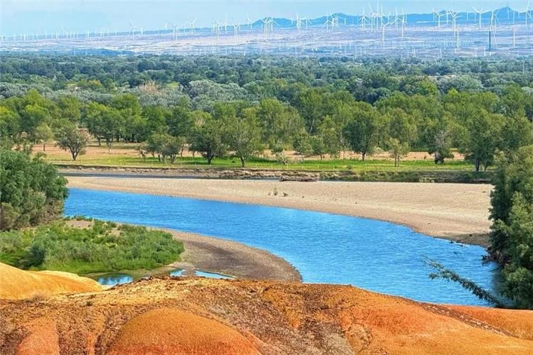 Colorful Beach Wucaitan, Irtysh River, Burqin Xinjiang Vibrant multicolored Yardan landform beside Irtysh River, dense poplar forest and wind turbines in distance, Colorful Beach Xinjiang