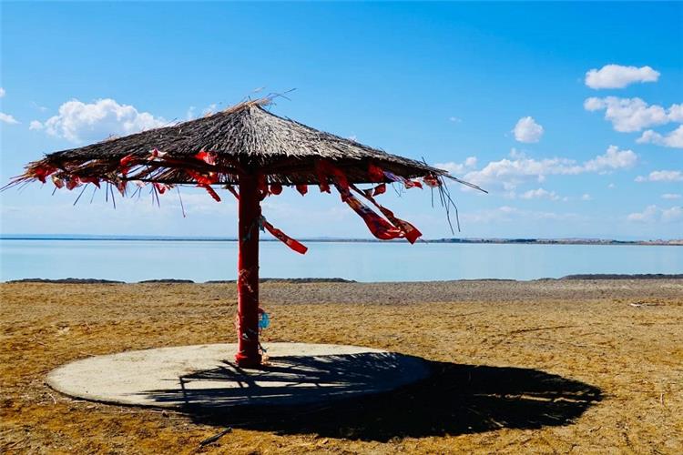 Ailik Lake, Gobi Freshwater Lake near Urho Ghost City Xinjiang Peaceful Ailik Lake under bright blue sky, straw sun shelter on dry gobi lakeshore, Xinjiang desert lake scenery