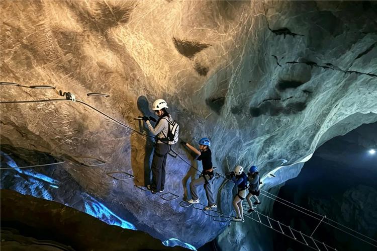 Visitors experiencing cave climbing and rope walk inside a rocky cave at Hangzhou OMG Heartbeat Park