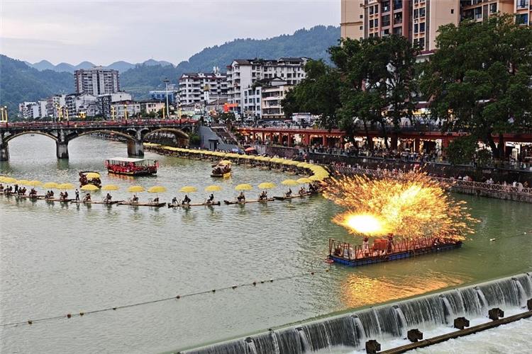 Gongshui river daytime iron fire show, long bamboo rafts with yellow umbrellas, stone arch bridge and townscape