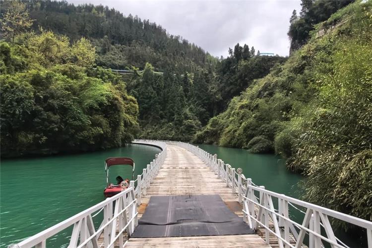Famous water floating bridge over emerald green river, lush mountain forest surrounding Shiziguan scenic area
