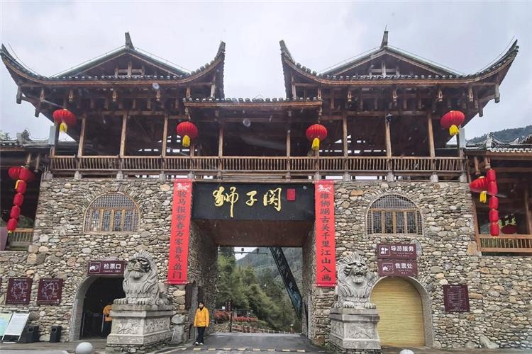 Traditional Chinese stone-and-wood gate of Shiziguan, stone lions, red lanterns and couplets at scenic entrance