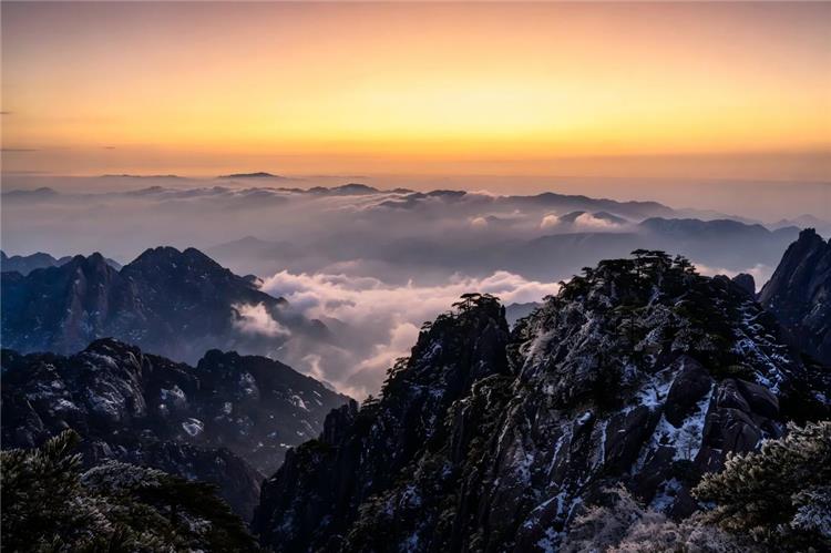 Huangshan Cloud Sea uangshan mountains rising above swirling clouds at sunrise