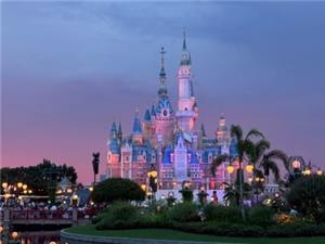 Twilight view of Shanghai Disneyland fairy-tale castle lit up with pink and purple glow.