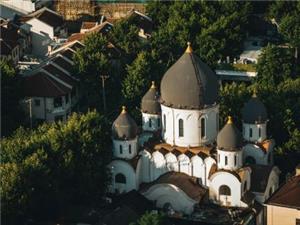 view of Shanghai Orthodox Church of the Mother of God, white onion domed building hidden among old shikumen houses and green trees