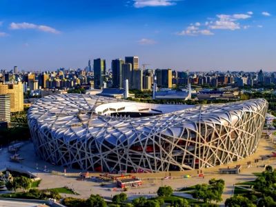 Aerial shot of the Bird's Nest National Stadium, iconic Beijing Olympic venue with downtown skyline and bright blue sky