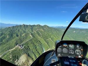 First-person view from helicopter overlooking winding Badaling Great Wall across green mountain ridges