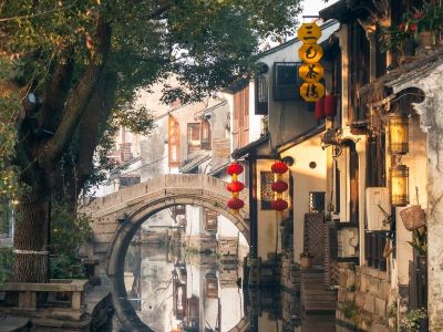 Classic round stone arch bridge, red lanterns and ancient white houses along canal in Zhouzhuang Water Town, Suzhou
