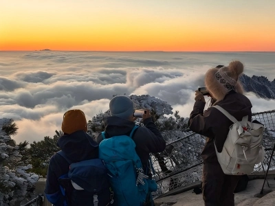 Backpack tourists photograph sea of clouds at Huangshan