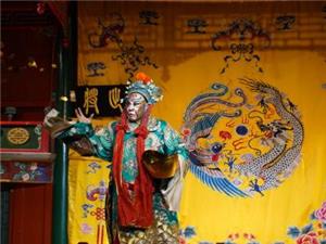 Peking Opera performer with vivid facial makeup and elaborate traditional costume on Huguang Guild Hall
