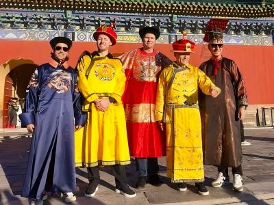 Five foreign visitors wearing ancient Chinese imperial robes pose for photos in front of the Temple of Heaven