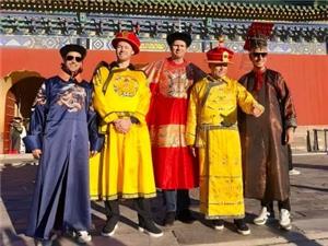 Five foreign visitors wearing ancient Chinese imperial robes pose for photos in front of the Temple of Heaven