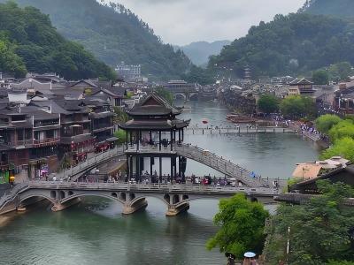 erial view of Fenghuang Ancient Town showing traditional Miao architecture, riverside buildings, and stone bridges