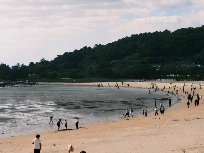 Seaside beach of Putuo Mountain, visitors along shoreline and green hills