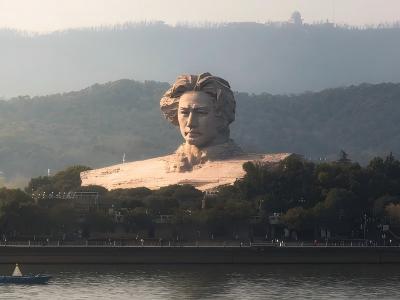 Young Mao Zedong statue at Orange Isle with mountains and Xiang River in Changsha, China