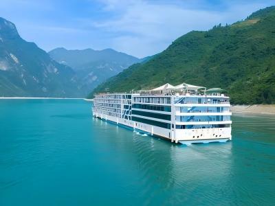 A white, multi-story luxury Yangtze River cruise ship sails through the Three Gorges