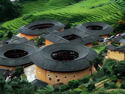 Traditional circular Fujian Tulou earth buildings surrounded by green rice terraces in Fujian
