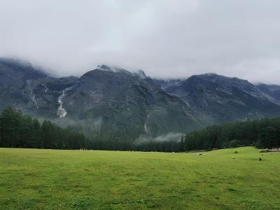 A scenic view of Jade Dragon Snow Mountain in Lijiang and mist-covered mountain peaks under a cloudy sky