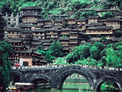 Traditional Buyi wooden stilt?house village, old stone arch bridge over river, Guizhou