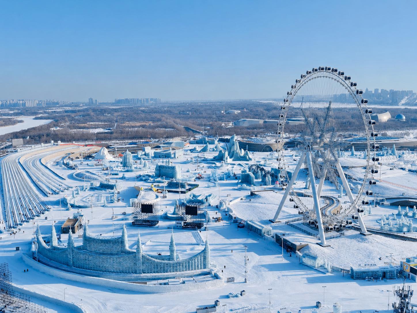 Snowflake-themed ferris wheel at Harbin Ice and Snow World with modern city high-rise buildings in background
